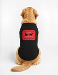 A golden retriever dog sitting with its back to the camera, wearing a black pet shirt with a red graphic on the back that reads 'LET'S SPEAK MY DOGS MAKE IT EASY'.